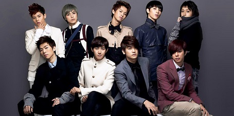 The nine members of the former K-Pop group, ZE:A. Fiive standing behind the four sitting members.