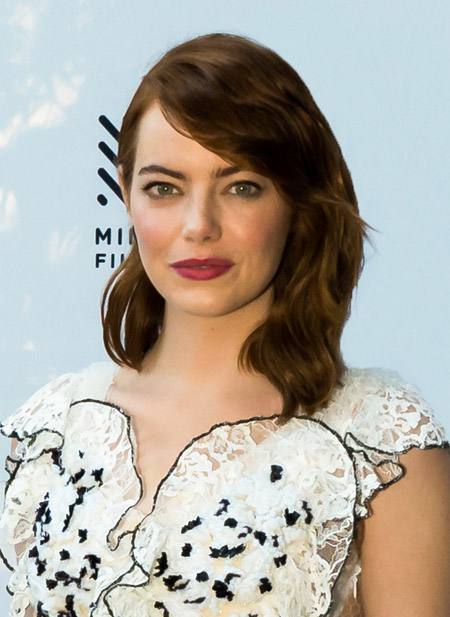 Emma Stone at a red carpet event wearing a white dress with black spots.