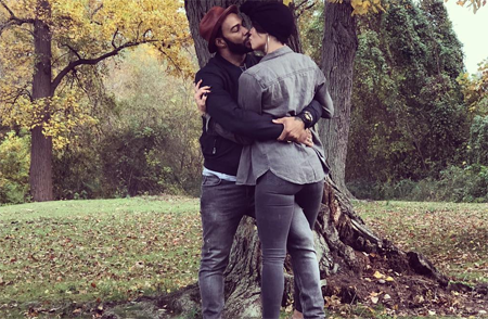 Omari Hardwick and his wife Jennifer Pfautch kissing under a tree.