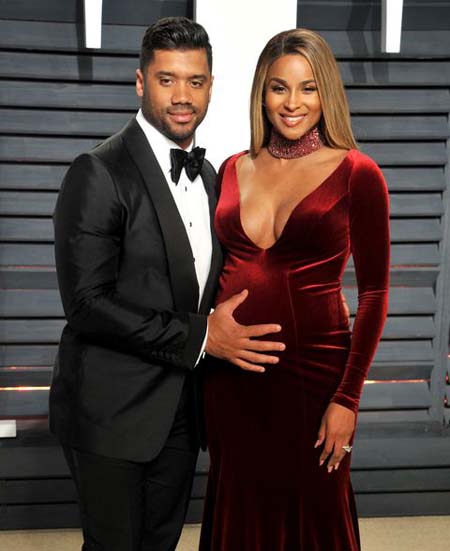 Russell Wilson with his hand over the pregnant belly of Ciara