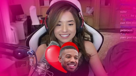 Pokimane in her gaming seat with headphones on as she smiles and a Michael Jordan headshot with a love sign behind it is displayed in front of the mic.