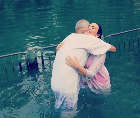 Demi Lovato hugging a baptizer in the holy river in Israel.