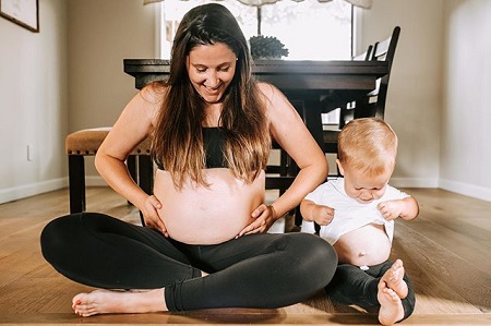 Tori grabbing her pregnant belly while sitting beside her son Jackson also attempting to do the same.