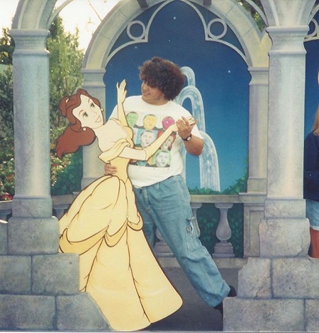 Jorge in his mid teens in a dancing position with a Disney Princess cutout..