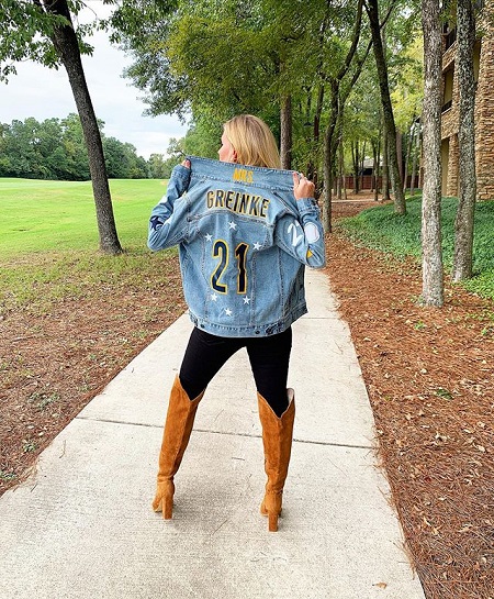 Greinke facing on her back while holding the collar of the Denim jacket she is wearing as described above.