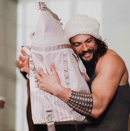 Jason hugging a bag from his product line that features a shark-teeth pattern.