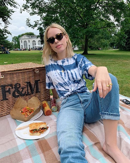 Burr sitting on a picnic sheet beside a picnic basket with a subway sandwich on a plate beside.