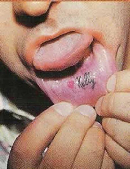 Malone extending his lower lip showing the '❤ Kelly' tattoo.