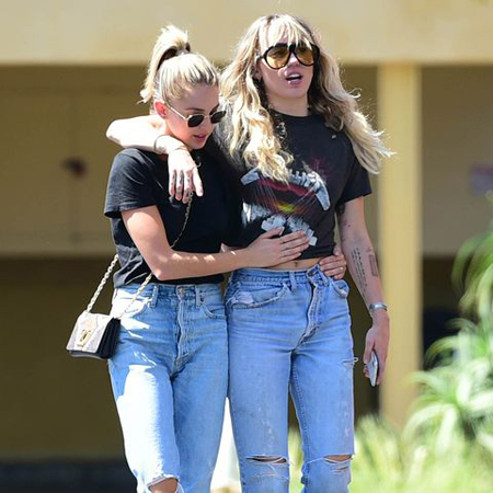 Miley Cyrus and Kaitlynn Carter walking together.