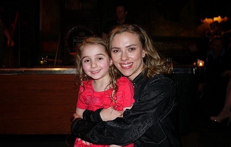 Scarlett in black hugging little Laurel, in red, from behind.