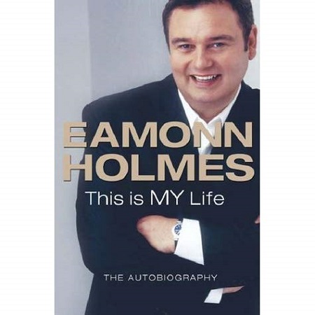 The cover of Eamonn's book 'This is MY Life'. Him folding his arms in a black suit and smiling at the camera.