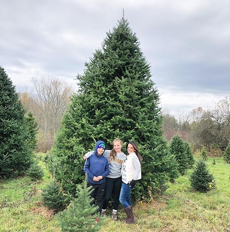 Hollie (right) with her daughter and son in front of a christmas tree before being cut down.