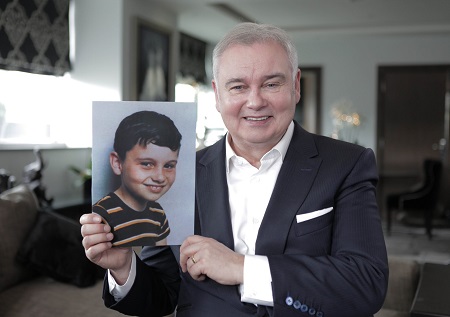 Eamonn holding up a photo of him as a child to his right. Both smiling.