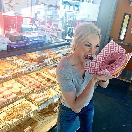 Liz Dueweke is holding a big donut, a food post she regularly does to promote her weight loss tactics.