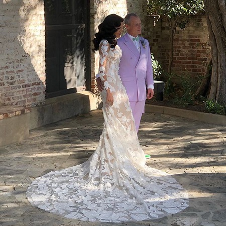 Melody Ehsani in her wedding dress with Michael 'Flea' Balzary looking at another camera.