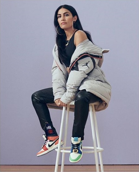Melody Ehsani sporting the colorful sneakers while sitting on a tool.