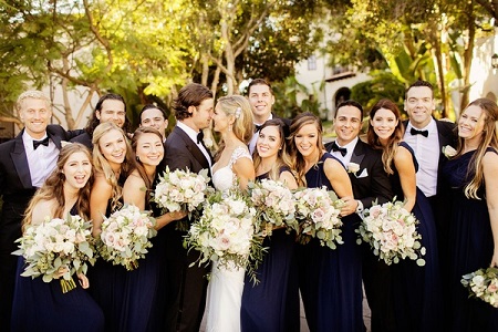 Gerrit Cole and Amy Crawford (looking at each other) centered by their friends all wearing black suits and blue dresses looking at the camera.