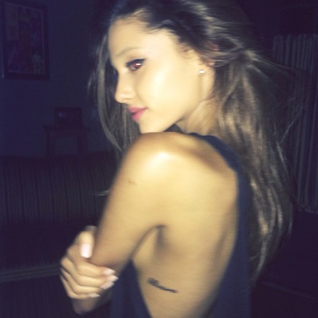 Ariana Grande showing her bellissima' tattoo while turning back.