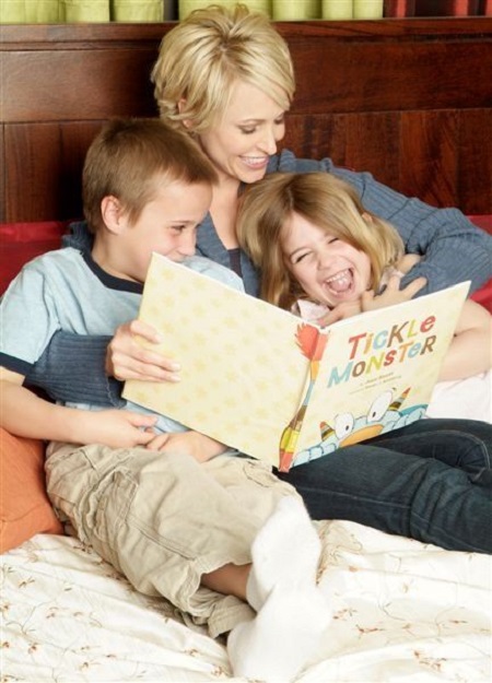 Bissett reading her kids 'Tickle Monsters' when they were young in a bed.