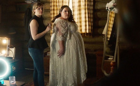 Chrissy (right) in her wedding dress from 'This Is Us' finale facing a mirror facing sideways with a helper behind her also looking sideways.