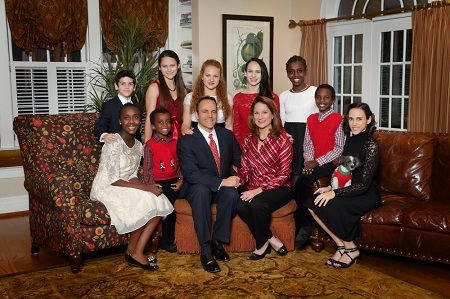 All nine children sitting beside their parents (in the middle) around two couches.