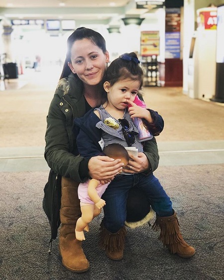 Jenelle Evans clutching her daughter Ensley on her lap, sitting.