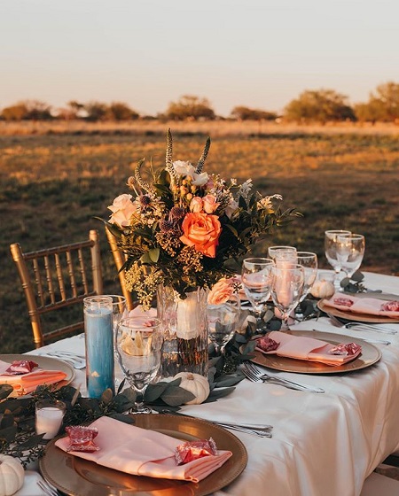 The wedding reception table with the bouquet centering the table. Plates and glasses appropriately placed.