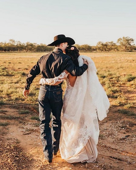 Lockwood and Kinsel with their respective arms crossing each other as they pose like walking away from the camera.