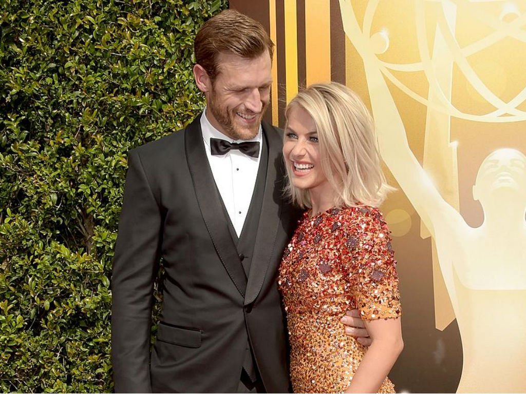 julianne in red/yellow sparkly dress and brooks in black tux. brooks hands around juliannes waist smiling 