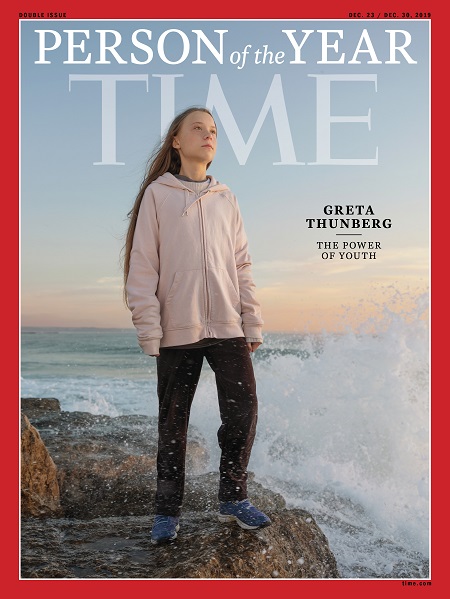 Greta Thunberg standing on a rock by the ocean with waves splashing in, as part of the cover of TIME magazine.