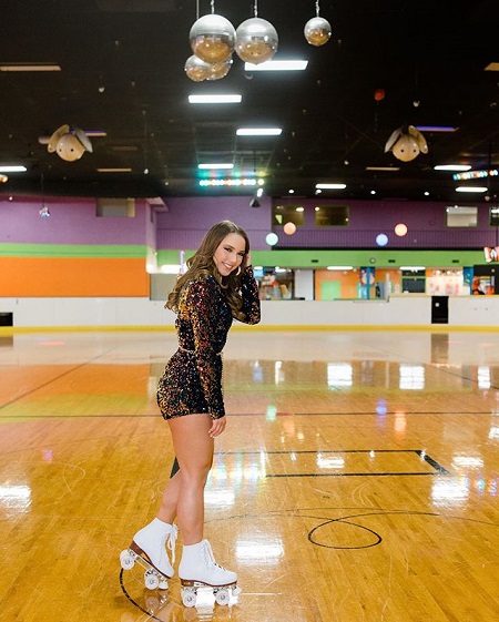 Eminem's daughter in a roller skate rink with the same outfit, plus skates in her shoes.