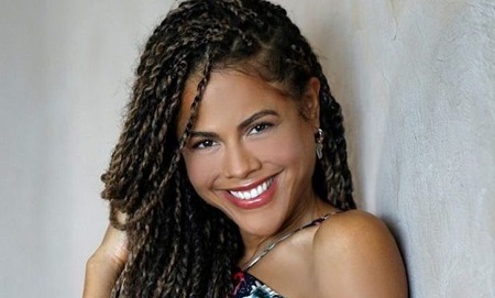 Lenora Crichlow headshot, smiling with braided hair pieces all over.