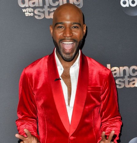 from the set of Dancing with the Stars, Karamo wearing a red suit with a white shirt, sporting a big smile.