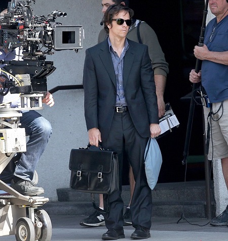 Wahlberg on the set of 'The Gambler' looking really thin and standing with a black briefcase.