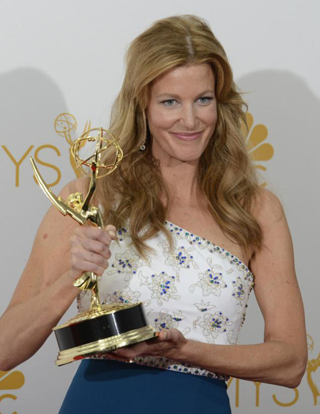 Anna Gunn, holding her Emmy with her right hand and smiling for the camera.