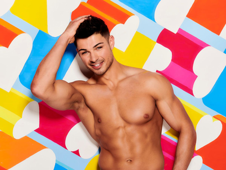 Anton Danyluk, bare chested, poses for the camera with his right hand slowly combing his hair.