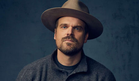 David Harbour look at the camera with a hat on.