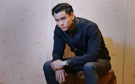 Eddie Peng is sitting on a log.