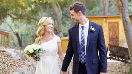 Angela in her wedding dress holds her husband's hand.