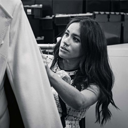 Meghan Markle looking at clothes inside a dressing room.