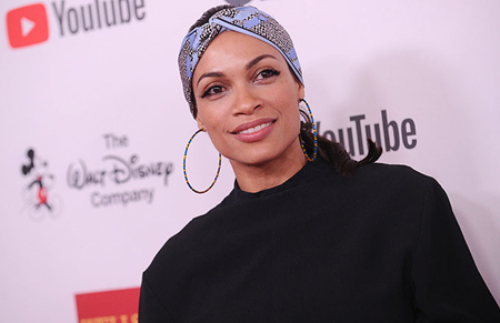 Rosario Dawson on a red carpet with a head scarf and huge ear rings