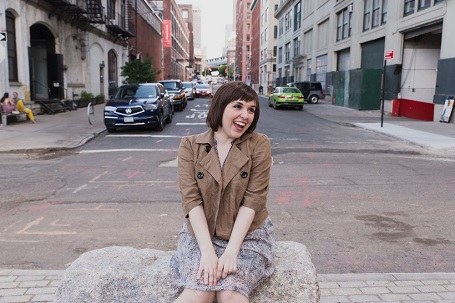 Bree laughing while sitting on a rock at the end of a street.