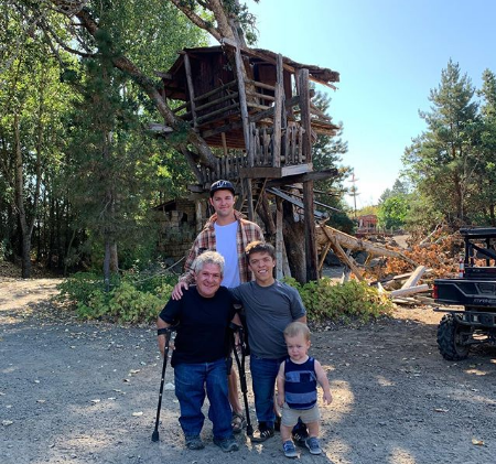 Matt near tree house with his two sons and a grandson
