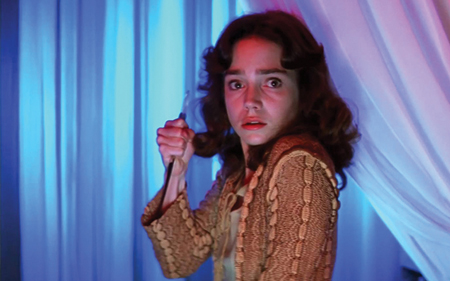 Jessica Harper looking scared with a knife in her hand.