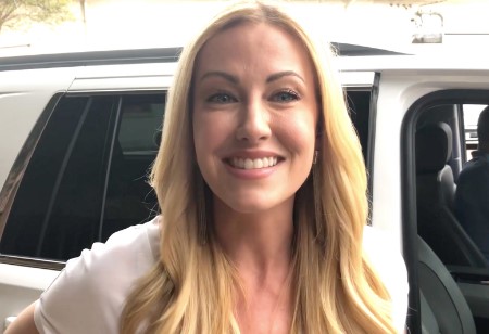 Stephanie standing infront of a car wearing a big smile.