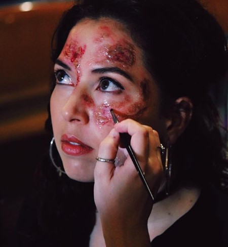 Christie doing a makeup for her play where the makeup artist drawing a scars on her face.