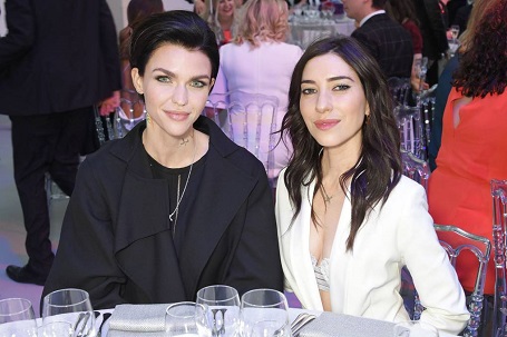 Ruby Rose and Jessica Origliasso sitting on a dinner table at Glamour Awards after-party. Ruby in black top and Jessica in white.