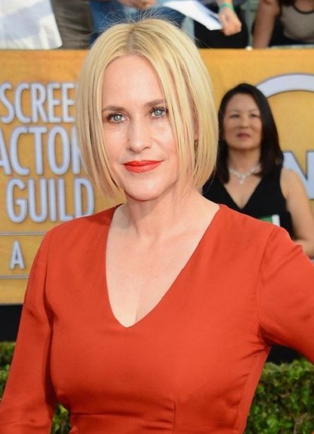 Patricia Arquette picks a tangerine pout to coordinate with her long-sleeved gown and YSL clutch at the 2014 SAG Awards.