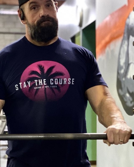 Ethan Suplee in the gym holding on to a weightlift bar.