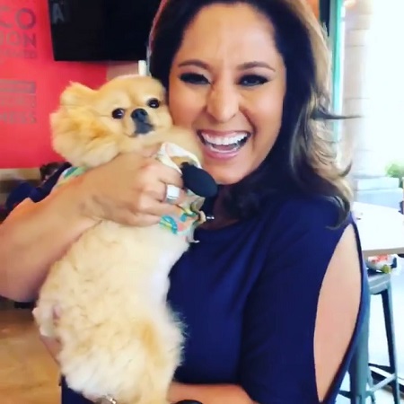 The Beautiful Lynette Romero smiling while holding a dog hugging her face.